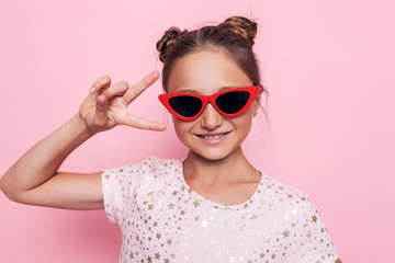Portrait of a glamorous teenage girl in dark glasses showing two fingers