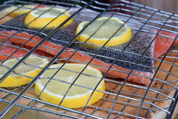 Salmon fillets with lemon slices in gridiron. Ready for barbecue.