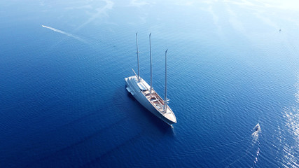 Aerial photo of sail boat cruising in deep blue waters of Santorini island, Cyclades, Aegean, Greece