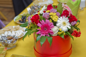 Beautiful bouquet of flowers in a box . Romantic red, white , yellow, purple roses in a red gift box to place the logo on a yellow background spring is coming,international women's day .
