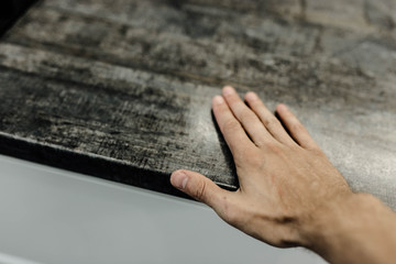 hand touches a wooden tabletop, tables made of solid oak.