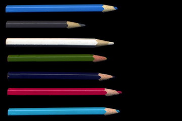 Old colored pencils lying on a black background