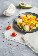 Fried pomelo with tomatoes and avocado on gray concrete background, side view.