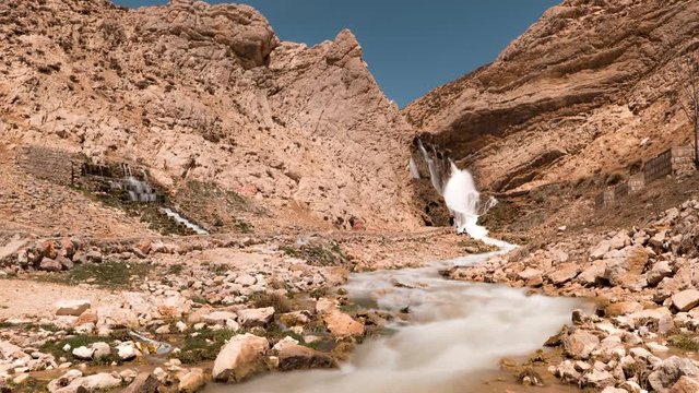 Beautiful timelapse of the dry cliffs around a small stream. Slow zoom in.