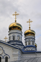 Fototapeta na wymiar Orthodox Christian Cathedral with golden domes and crosses against the sky, spring day. Sobor Tikhvinskoy Ikony Bozhiyey Materi, Tsivilsk, Russia