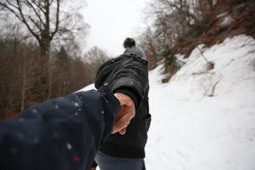 Fototapeta na wymiar Pareja tirando de la mano bajo la nieve