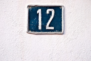 Number 12 / twelve, rustic plate number on the wall.