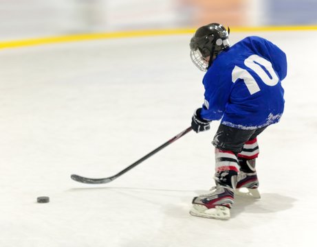 Young Child Playing Hockey On Ice