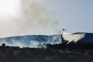 Helicopter launching water during a forest fire