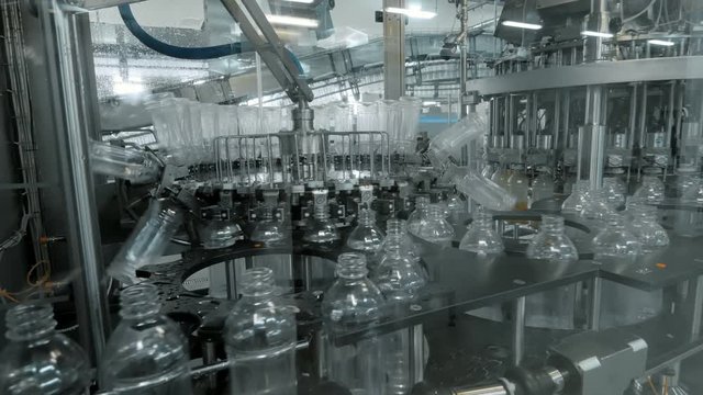 Plastic bottles inside industrial machine conveyor line or belt preparing for filling with drink. Water and juice bottling plant