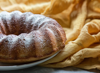 Pumpkin cake on a white dish on yellow fabric. 