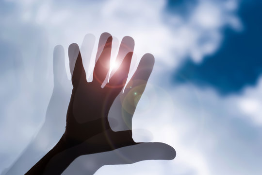 blurred hand against the cloudy sky with glow of light,confusion,blurry sight,day dream,concept image