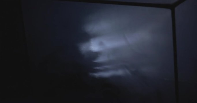 Glowin futuristic hologram projection of dark face anonymus hacker in the black box with glass and smoke. Future comunication concept. Laser effect.