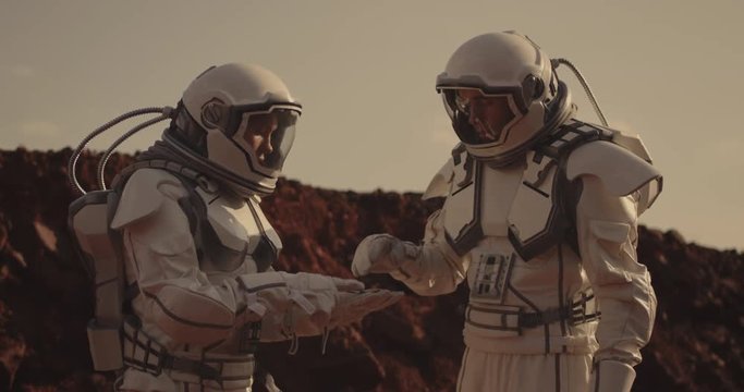 Two astronauts examining sample on Mars