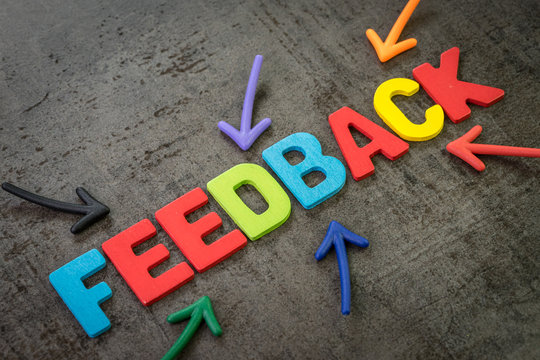 Customer feedback, review or rating concept, multi color arrows pointing to the word Feedback at the center of black cement chalkboard wall
