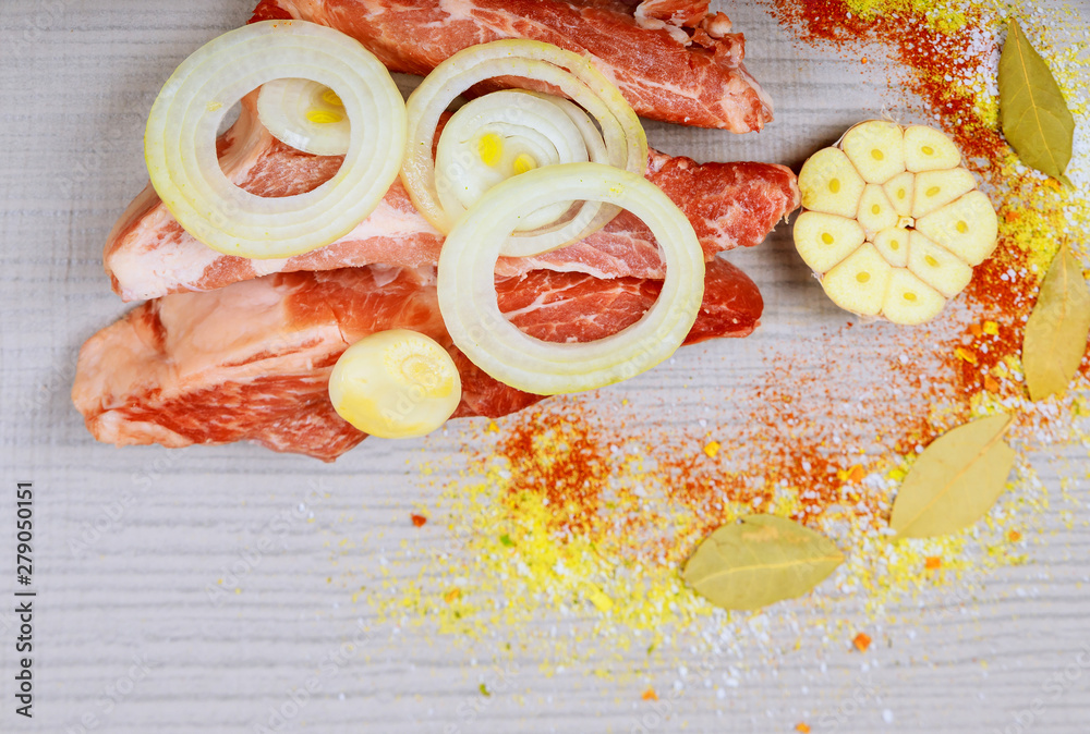 Wall mural Raw pork steak with onion on a white wooden table