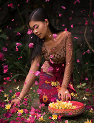 Asian girl. Beautiful Balinese women in traditional dress collects yellow plumeria frangipani...