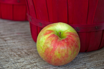close up of ripe apple by red bushel basket