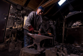 blacksmith manually forging the molten metal