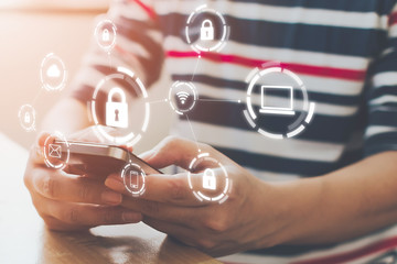 Close-up image of male hands using mobile smartphone with icon graphic cyber security network of...