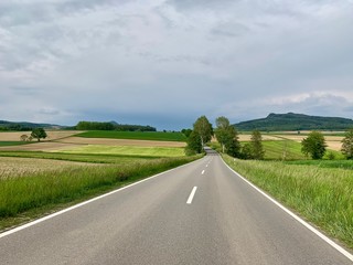 Fototapeta na wymiar Leere Landstrasse - Autostrasse durch Landwirtschaftszone - Felder und Wiesen