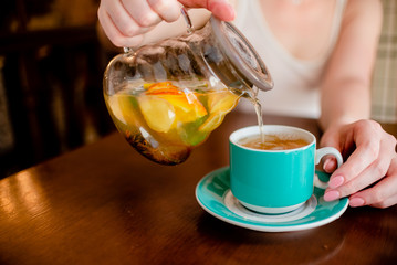 Female hands holding tea pot  hot green tea cup beverage, drinks citrus . Horizontal several objects copyspace
