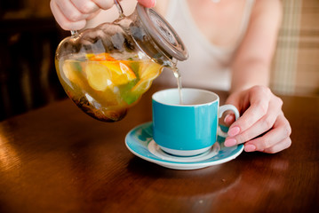 Female hands holding tea pot  hot green tea cup beverage, drinks citrus . Horizontal several objects copyspace
