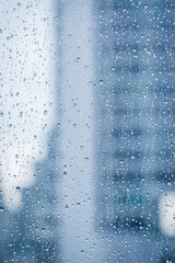 Abstract image of Rain drops on the dirty glass windows with modern office building