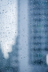 Abstract image of Rain drops on the dirty glass windows with modern office building