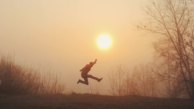 Silhouette of funny crazy man dancing against sunrise or sunset. successful joyful and cheerful man dancing on the background of the sun.