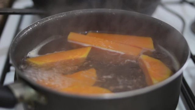 closeup uncovering pot cooking squash in boiling water with glass cover