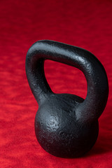 Fototapeta na wymiar Holiday fitness, black kettle bell on a multi-shade red background 