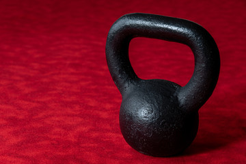 Fototapeta na wymiar Holiday fitness, black kettle bell on a multi-shade red background 