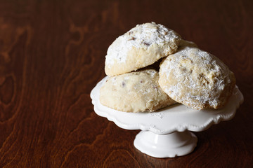 Stack of Russian Tea Cake cookies on a white cake plate on a dark brown wood table