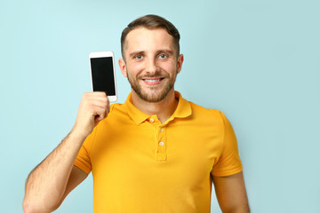 Handsome man with mobile phone on color background