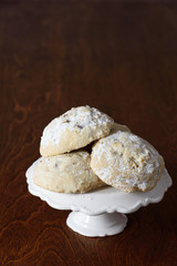 Stack of Russian Tea Cake cookies on a white cake plate on a dark brown wood table