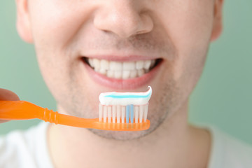 Man with toothbrush on color background, closeup. Concept of dental hygiene