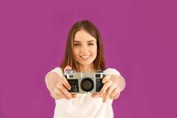 Young female photographer on color background