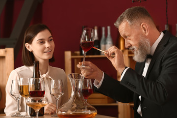 Mature sommelier with his student in wine cellar