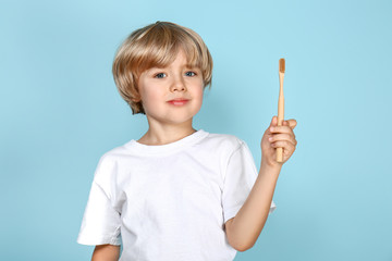 Cute little boy brushing teeth on color background