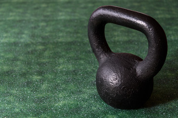 Fototapeta na wymiar Holiday fitness, black kettle bell on a multi-shade green background with white sparkles