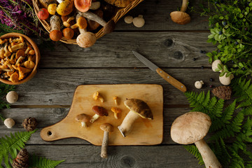 Mushrooms on old wooden background. Card on autumn or summertime. Forest harvest. Boletus, chanterelles, leaves, berries. Flat lay.