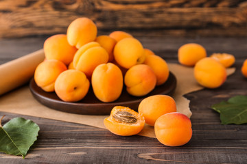 Plate with tasty ripe apricots on wooden table