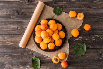 Plate with tasty ripe apricots on wooden table