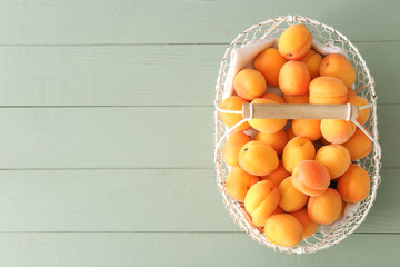 Basket with tasty ripe apricots on wooden table