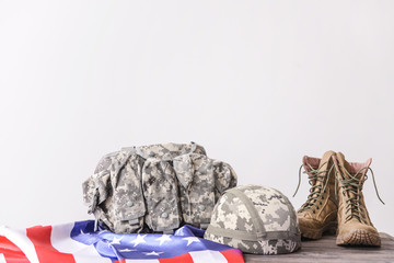 Military helmet, vest, boots and USA flag on table