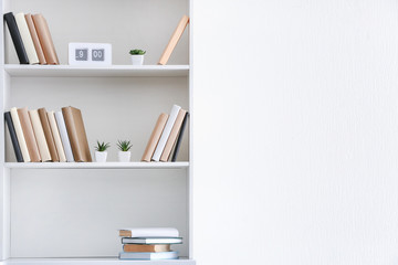 Shelf unit with books near white wall © Pixel-Shot