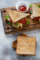 Sandwiches with grain bread, chicken fillet, cheese and vegetables, vertical shot, elevated view