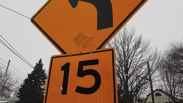 Slow Motion Shot Walking Up To An Orange Turn Left Traffic Sign With Recommended Speed Limit In New York On A Winter Snowy Day - Snow And Cold - 1080p 60fps