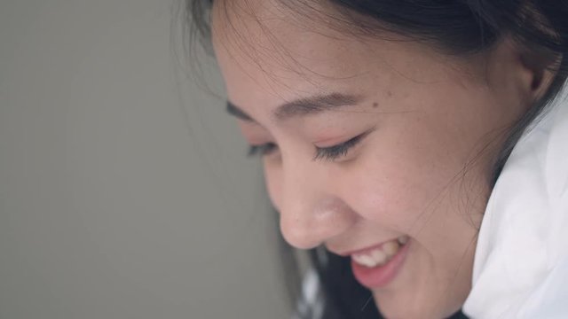Close up portrait Asian woman smiling and using a tablet on the bedroom browsing online social media sharing lifestyle.